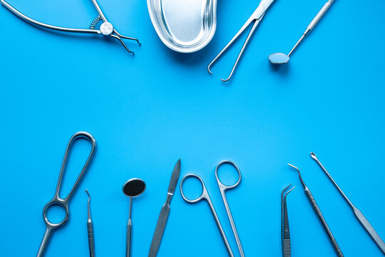 Set of stainless surgical instruments and tools - scalpels, scissors and others - on blue table, top view