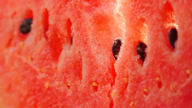 Close-up of watermelon flesh revealing seeds and texture, showcasing the vibrant red color and juicy interior in a natural setting