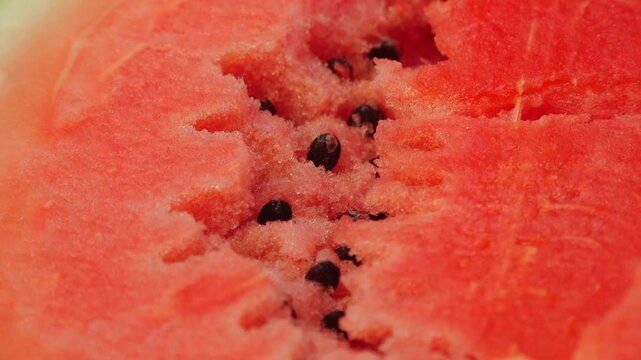 Close-up of sliced watermelon revealing juicy red flesh and black seeds, showcasing the fresh fruit's texture and vibrant color in detail