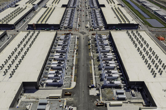Aerial view of a large data center facility featuring rows of cooling units on rooftops, paved access roads, and industrial infrastructure in Indiana, United States.