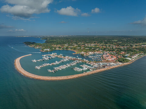 Aerial view of Marina Casa de Campo with numerous yachts docked in the harbor protected by a stone breakwater along the coastline of La Romana, La Romana, Dominican Republic.