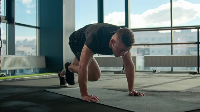 Caucasian athlete man male doing mountain climber exercise fitness mat in side gym sportsman running plank bending knees intense cardio workout endurance training abdominal muscles healthy lifestyle
