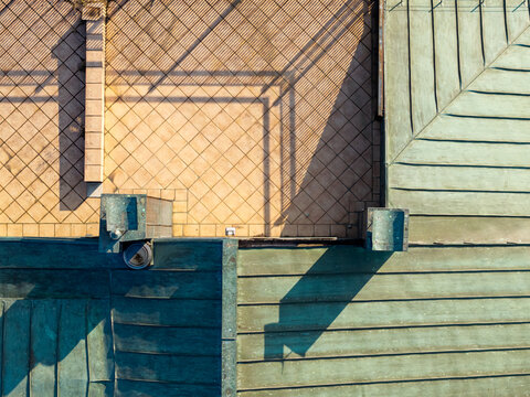 Aerial view of architectural rooftop geometry featuring a tiled terrace and metal roof panels with long shadows in Belgrade, Serbia.