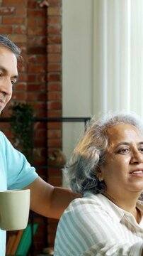 Indian Asian couple in their fifties with grey hair enjoying quality time together as they review a painting at home, with the wife holding a brush and the husband providing feedback