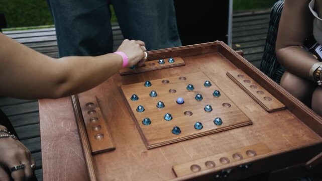 Women are playing a board game sitting at a table on the terrace. Close-up shooting