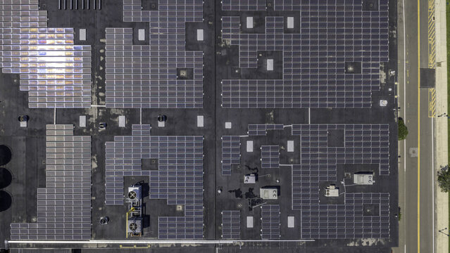 Aerial view of solar panels installed on an industrial rooftop with HVAC units and adjacent road in Derby, CT, United States.