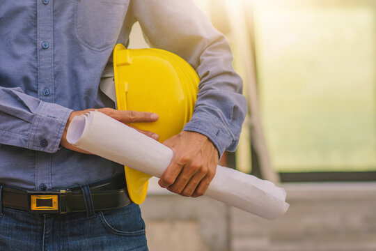 construction worker with hammer. Architecture Engineer holding hard hat on site building construction background