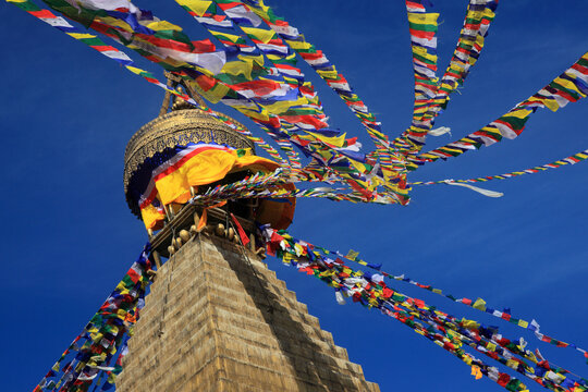 Boudhanath Stupa decorated with colorful Buddhist prayer flags against a deep blue sky in Kathmandu, Nepal