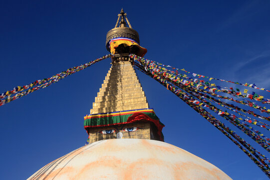 Boudhanath Stupa decorated with colorful Buddhist prayer flags against a deep blue sky in Kathmandu, Nepal