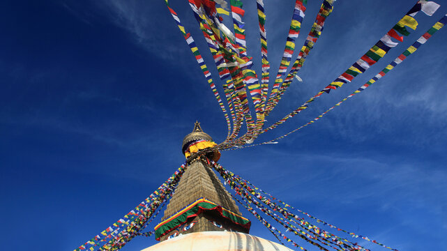 Boudhanath Stupa decorated with colorful Buddhist prayer flags against a deep blue sky in Kathmandu, Nepal