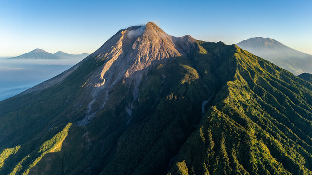 Aerial view of Mount Merapi, an active volcano with rugged slopes, lush green vegetation, and rocky terrain in Yogyakarta, Special Region of Yogyakarta, Indonesia.