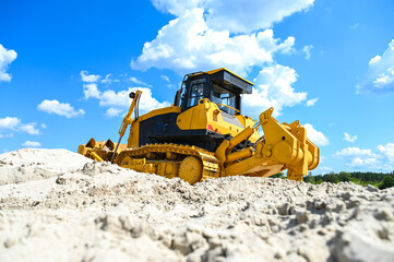 Modern bulldozer working on sand at a quarry or construction site. Heavy machinery moving and leveling sand during earthmoving and industrial operations. © senssnow