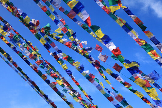Colorful Tibetan Buddhist prayer flags fluttering against a clear blue sky, symbolizing peace, compassion, spirituality and Buddhist tradition