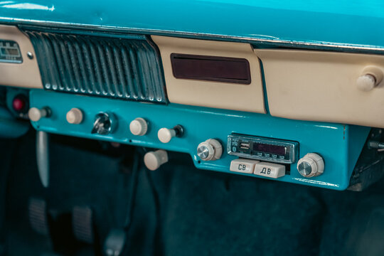 Minsk, Belarus - 08.08.2026: A turquoise and cream vintage car dashboard features row of mechanical switches and an original radio player with modern digital updates.