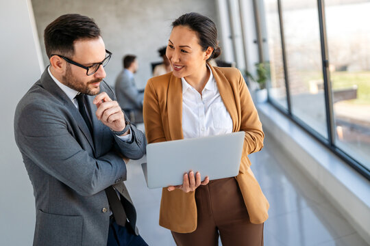 Two happy diverse multiethnic business team people working, talking in corporate office