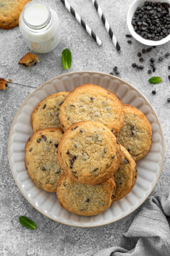 Chocolate chip cookies with milk on a plate on a gray concrete background. Homemade bakery cookies. Top view.