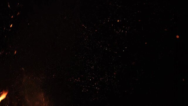 Fiery embers rise against a dark backdrop during a dramatic cinematic display of burning particles