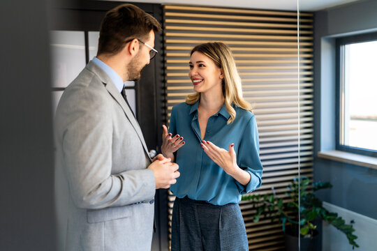 Two happy diverse multiethnic business team people working, talking in corporate office
