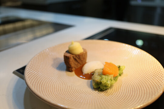 A beautifully plated gourmet creation features succulent meat paired with vibrant vegetable puree. This culinary delight sits on a modern table, inviting taste and admiration.