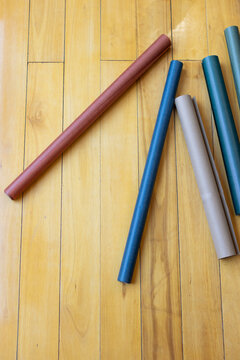 Cylindrical paper tubes resting diagonally on varnished wooden floor with soft shadows, copy space