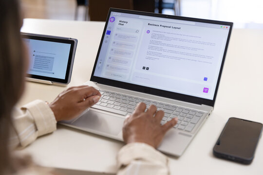 Woman with cuffs typing proposal on laptop with chat at office tablet and phone nearby