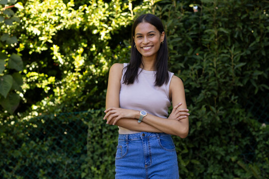 African woman standing smiling in backyard by chain-link fence wearing denim skirt, wristwatch