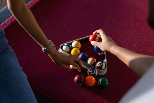 African American friends in jeans steadying triangle rack placing numbered balls on burgundy felt