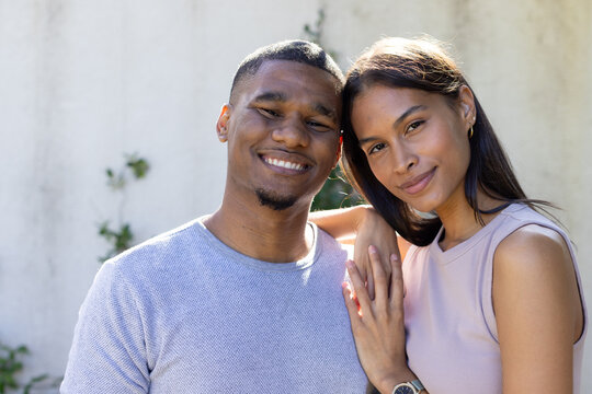 African American couple posing together in courtyard, showing wristwatch and earrings