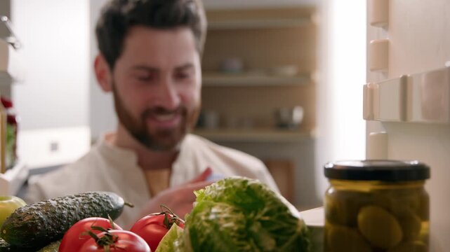 POV inside refrigerator Caucasian vegetarian man drinking cold water from fridge indoor kitchen male homeowner opening full freezer fresh vegetables healthy lifestyle refreshment hydration diet food