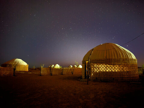 View of traditional yurts illuminated at night under a starry sky in the desert landscape near the Darvaza Gas Crater, Derweze, Dasoguz Region, Turkmenistan.