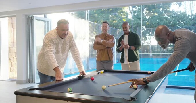 Diverse male friends reacting after senior man leaning, striking cue ball at pool table