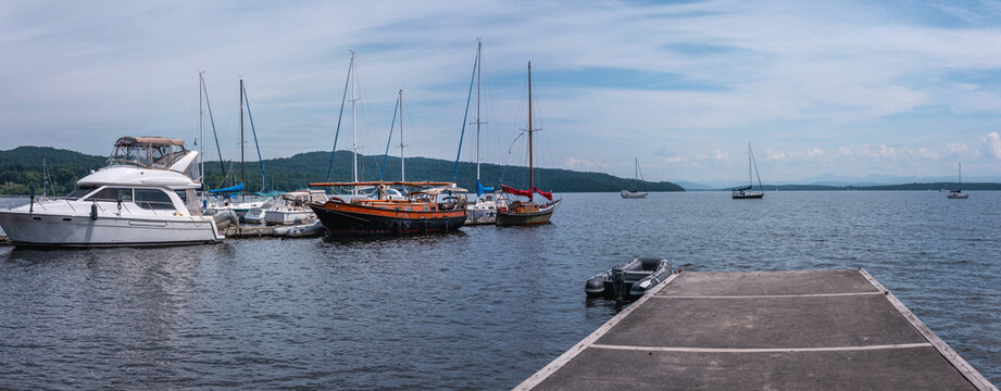 Lake Champlain summer landscape with moored boats, yachts, and walking dock in New York