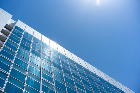 Glass Facade Office Building Under Blue Sky for Modern Architecture Corporate Vision and Real Estate Investment Background, Low Angle Perspective Photo with Copyspace