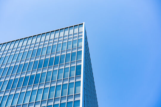 Glass Facade Office Building Corner Under Blue Sky for Modern Architecture Corporate Growth and Real Estate Investment Background, Low Angle Perspective Photo with Copyspace