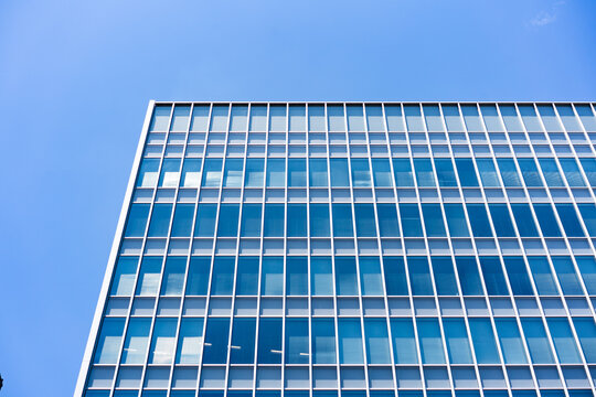 Glass Facade Office Building Corner Under Blue Sky for Modern Architecture Corporate Growth and Real Estate Investment Background, Low Angle Perspective Photo with Copyspace