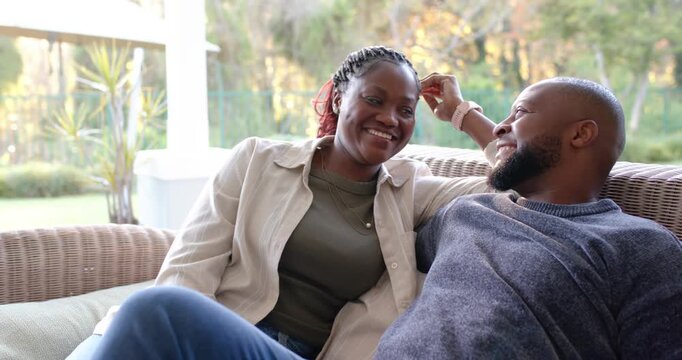 African couple cuddling woman touching braided hair leaning close on wicker sofa posing for camera