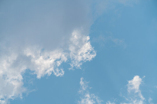 Clouds drift in the blue sky above on a clear day with sunlight shining through the wispy clouds
