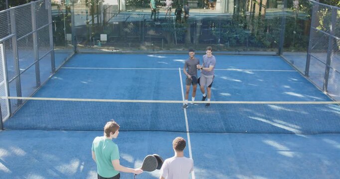Restarting Diverse male players meeting at net, tapping paddles, preparing to play on blue court
