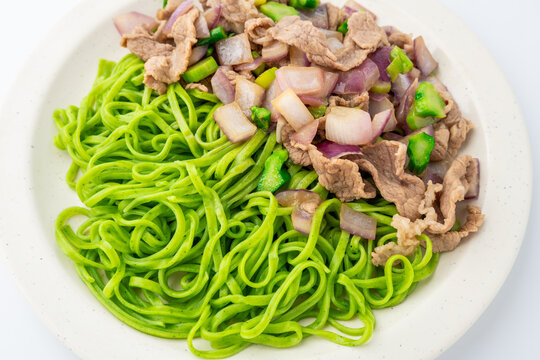 A plate of spinach noodles tossed with beef and onions