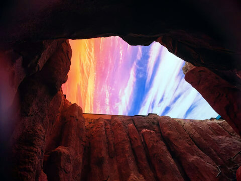 View of the dramatic sandstone rock formations of Wadi Rum Protected Area framing a vibrant sunset sky with colorful clouds in Aqaba Governorate, Jordan.