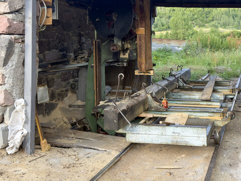 View of a stationary sawmill machine cutting a large wooden beam in an open-sided shed in Posof, Ardahan, Turkiye.