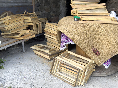 View of wooden beehive frames stacked on a table and floor in a rustic workshop in Posof, Ardahan, Turkiye.