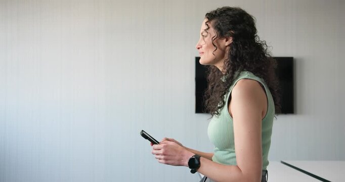African American woman leaning reading phone message turning to camera smiling in office copy space