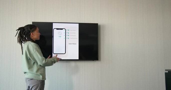 Nonbinary African American presenting in meeting reaching screen, walking, pointing at Client Notes