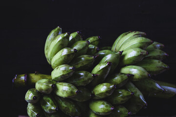 Fresh green bananas on the dark background © Thai