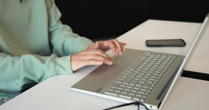 African American nonbinary at desk, opening silver laptop, typing and using touchpad for work