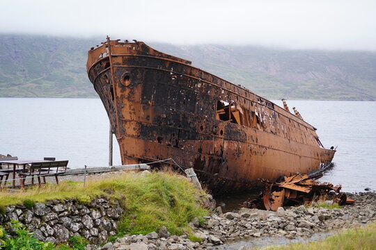 View of the rusted Sudurland shipwreck resting on the rocky shore in Djupavik, Arneshreppur, Iceland.