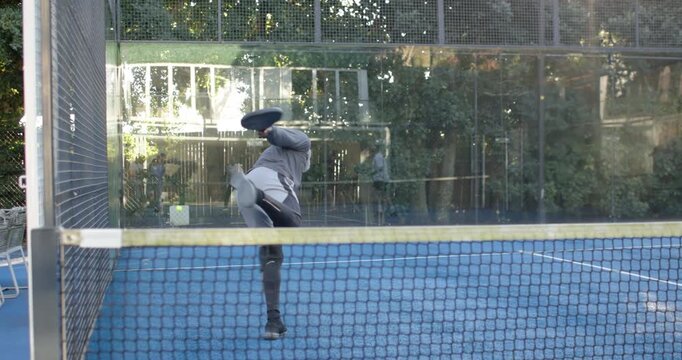 Senior man lunging for fast ball, sliding, running smash with paddle to score, partner cheering