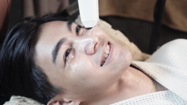 Satisfied male client receiving a 2D HIFU facial session in an aesthetic clinic for noninvasive skin tightening and rejuvenation.v