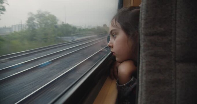 Little girl looks out train window on way to Toronto airport